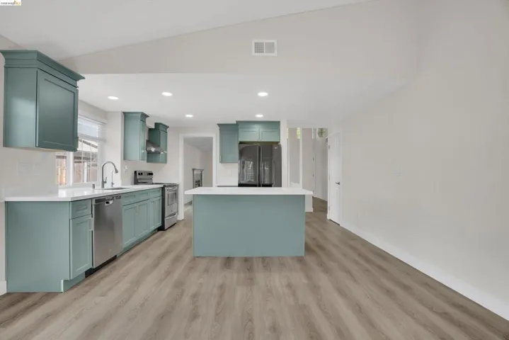 Kitchen featuring a center island, stainless steel appliances, light wood finished floors, green cabinetry, and recessed lighting