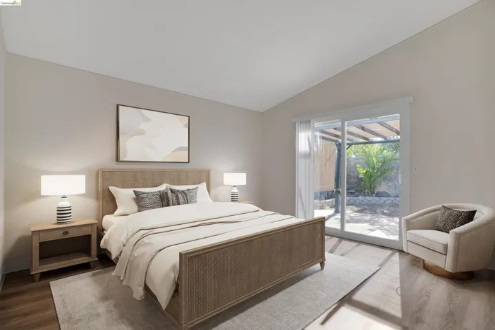 Bedroom featuring vaulted ceiling, wood finished floors, and access to exterior