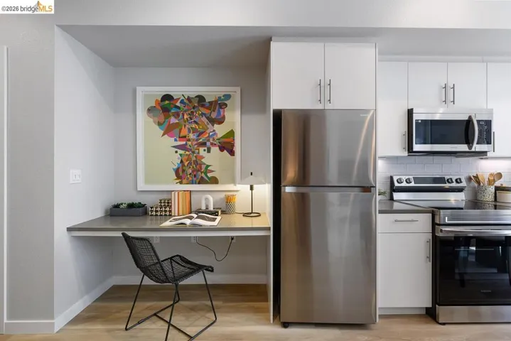 Kitchen featuring stainless steel appliances, light wood-style flooring, white cabinets, a kitchen bar, and backsplash