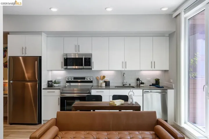 Kitchen featuring appliances with stainless steel finishes, dark countertops, white cabinets, decorative backsplash, and open floor plan