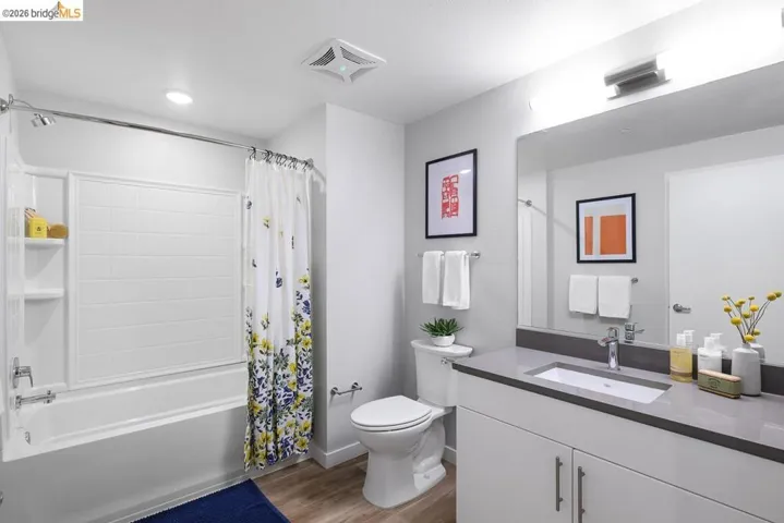 Bathroom with shower / bathtub combination with curtain, light wood-style flooring, and vanity