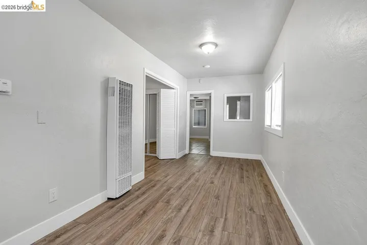 Unfurnished bedroom featuring wood finished floors, a heating unit, and a textured wall