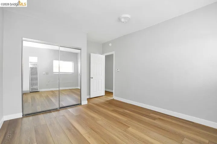 Unfurnished bedroom featuring light wood-type flooring, a closet, and a heating unit