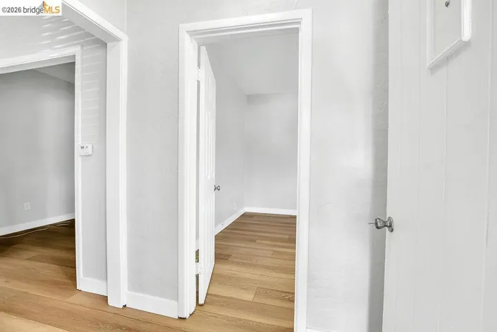 Hallway with light wood-style flooring and a textured wall