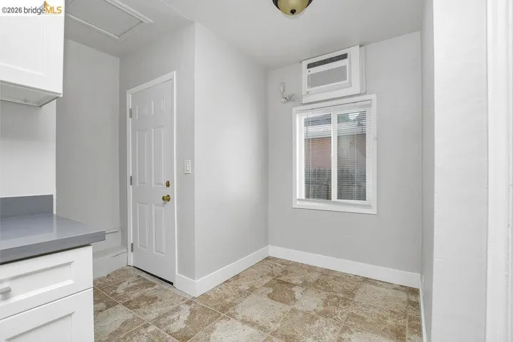 Laundry room with baseboards and a wall unit AC