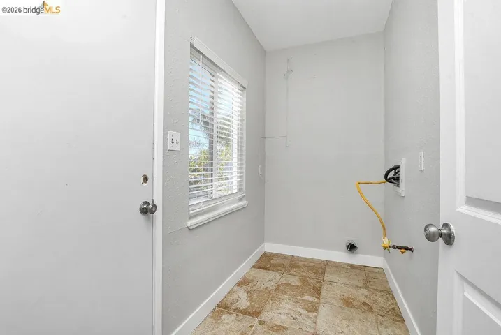 Laundry room featuring light stone finish floors and baseboards