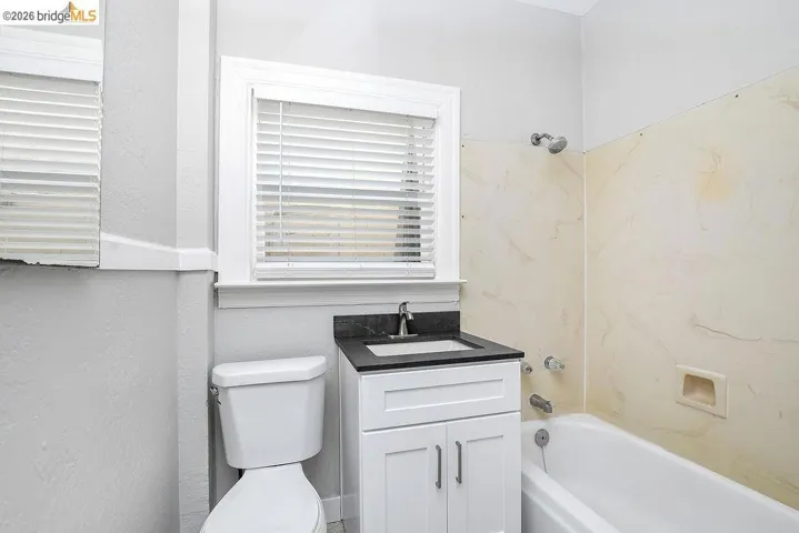 Full bath with bathing tub / shower combination, vanity, and a textured wall