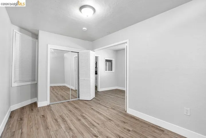 Unfurnished bedroom with light wood-style floors, a closet, and a textured ceiling