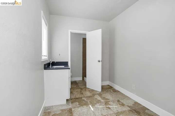 Laundry area with baseboards and stone finish flooring