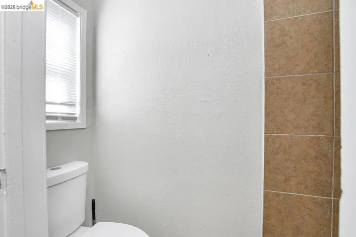 Bathroom featuring toilet and a textured wall