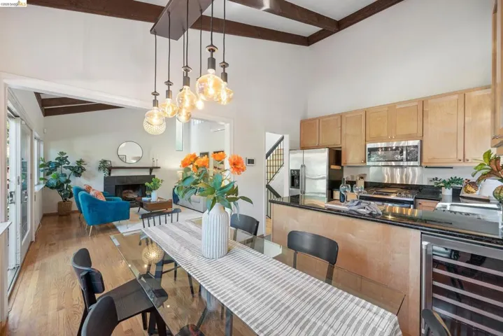 Kitchen featuring beverage cooler, dark stone countertops, a fireplace, decorative light fixtures, and stainless steel appliances