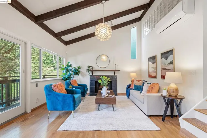 Living room featuring a fireplace, light wood-type flooring, and lofted ceiling