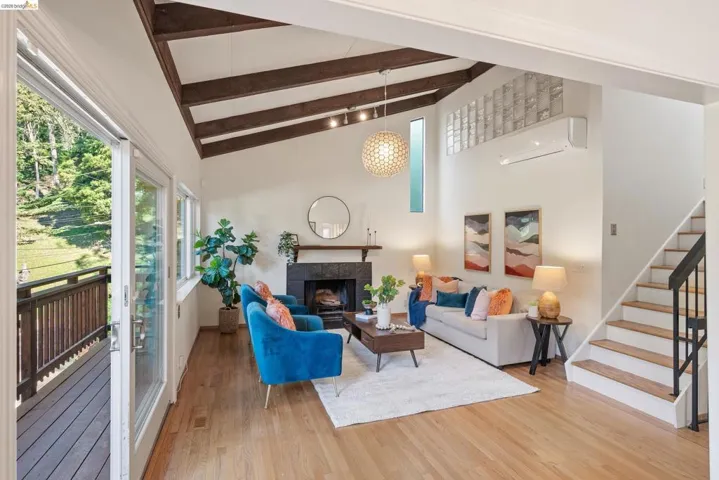 Living area featuring light wood finished floors, a tiled fireplace, and vaulted ceiling