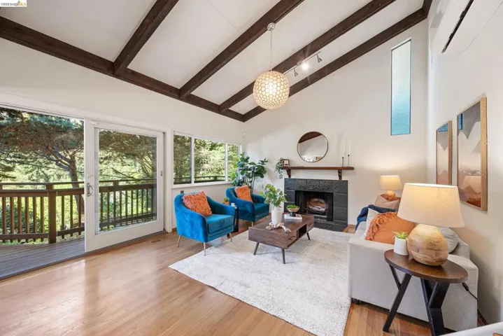 Living area with vaulted ceiling, wood finished floors, and a tile fireplace
