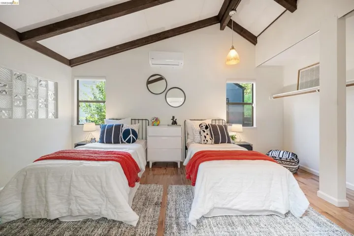 Bedroom with wood finished floors and a wall mounted mini split