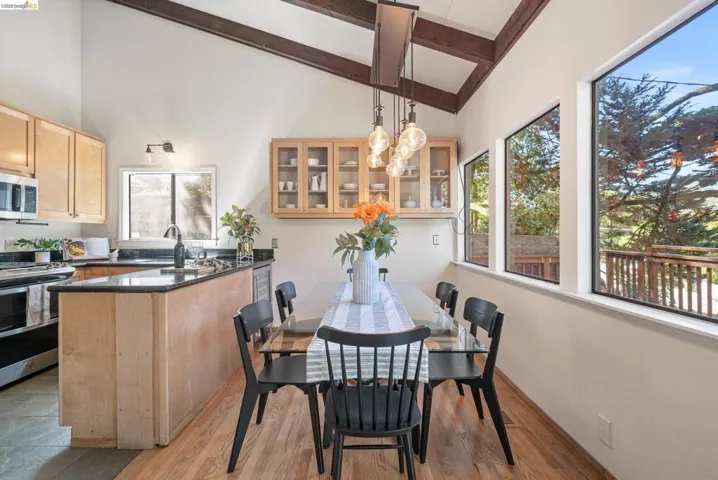 Dining area with vaulted ceiling and light wood-type flooring