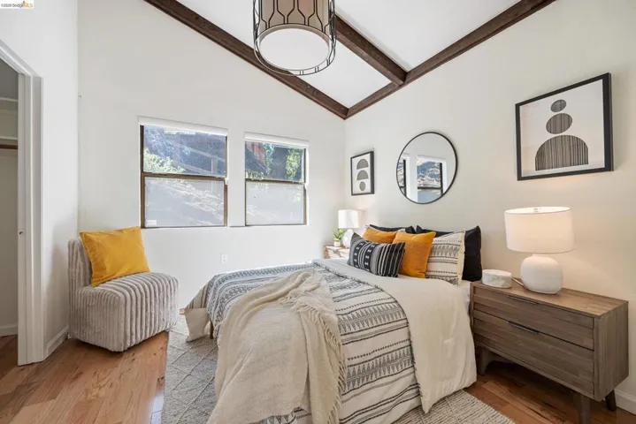 Bedroom with lofted ceiling with beams and wood finished floors
