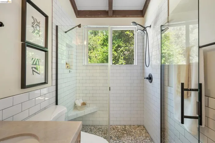 Bathroom with vanity, a shower stall, and tile walls