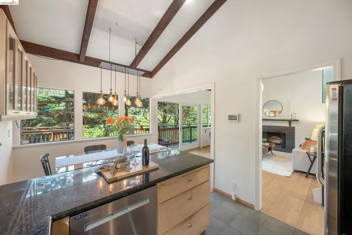 Kitchen featuring stainless steel appliances, a tile fireplace, hanging light fixtures, glass insert cabinets, and dark stone countertops