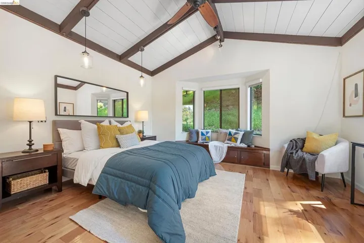 Bedroom with light wood-style floors and beamed ceiling