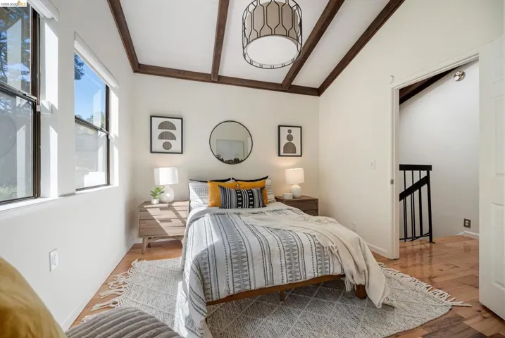 Bedroom with wood-type flooring and lofted ceiling with beams