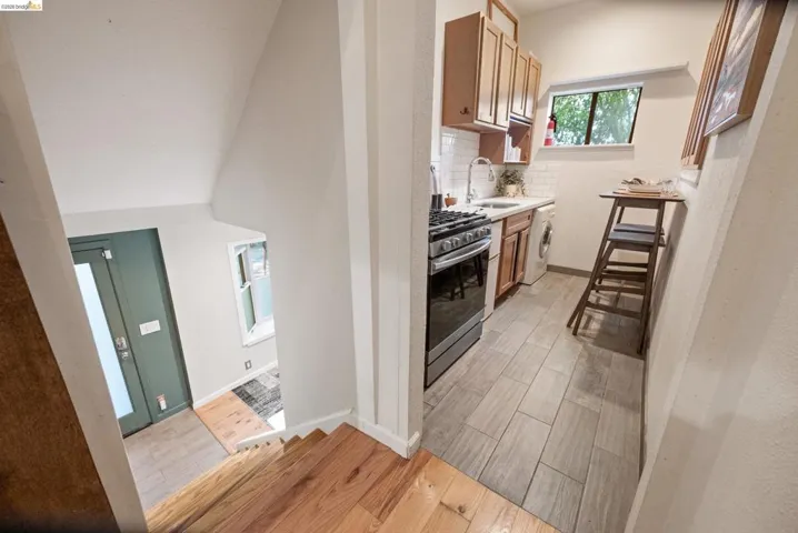Kitchen featuring wood tiled floors, gas stove, light countertops, backsplash, and washer / clothes dryer