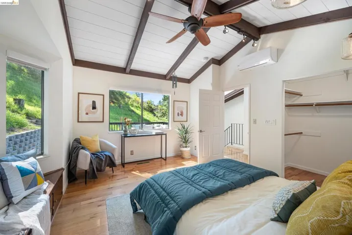Bedroom with light wood-style floors, a spacious closet, and a wood ceiling with exposed beams