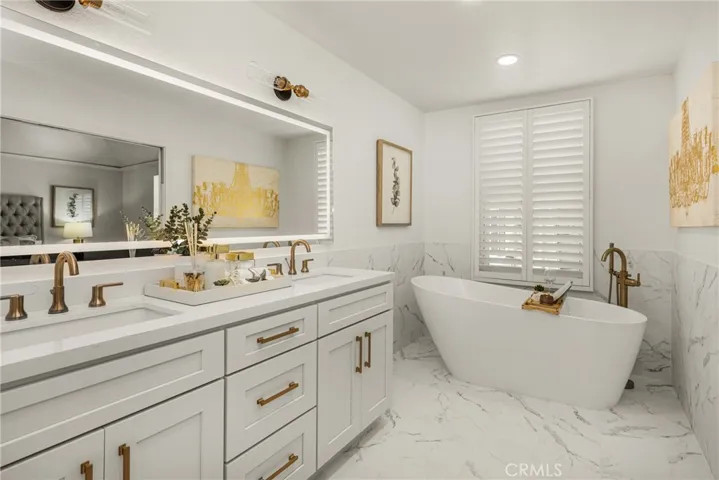 Primary bath is freshly remodeled with a new vanity, soaking tub, Carrera marble floor tile, mirror and fixtures.