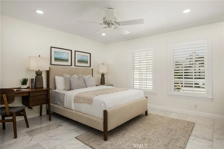Downstairs bedroom features a ceiling fan, recessed lighting and plantation shutters.