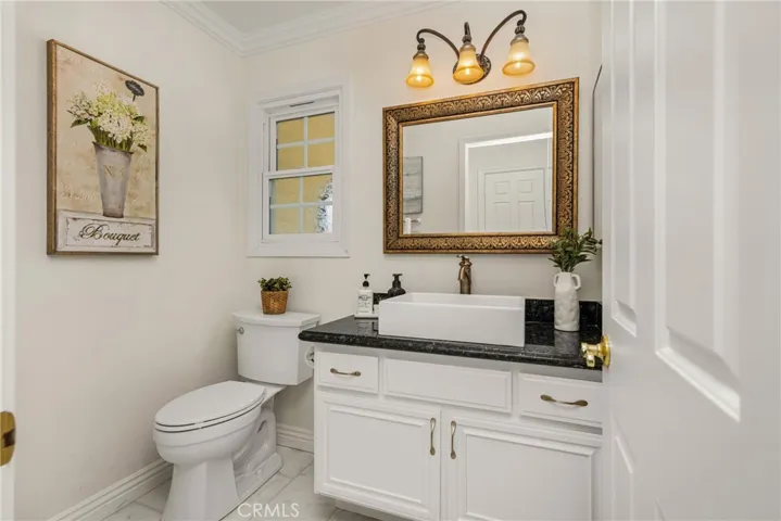 Downstairs guest bath offers an updated vanity with vessel sink and a new Carrera marble floor.
