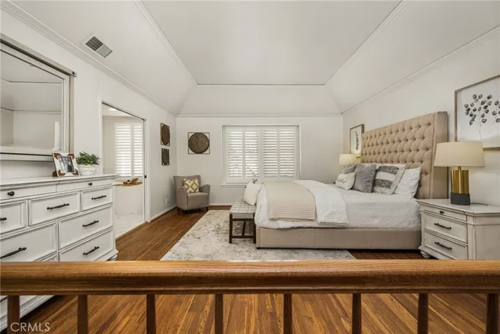 The spacious primary suite offers hardwood floors, plantation shutters and a coved ceiling, all adding warmth and comfort to this space.