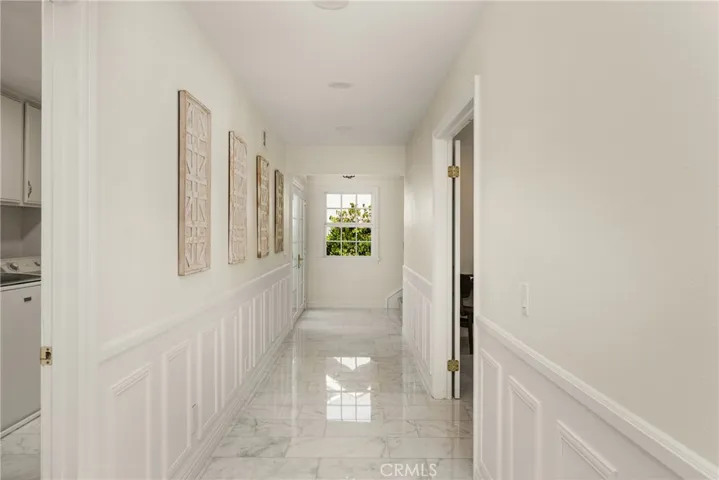 Hallway to the right of the front entry elegantly leads to the laundry room and downstairs bedroom.