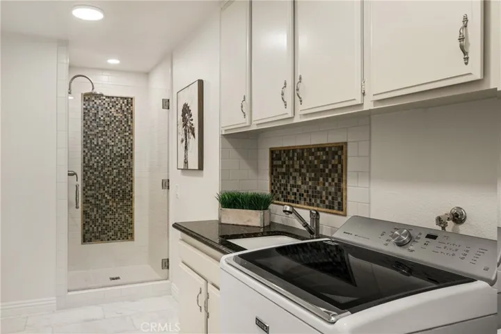 Across from the guest bath is a large laundry room with ample storage and a walk-in shower!
