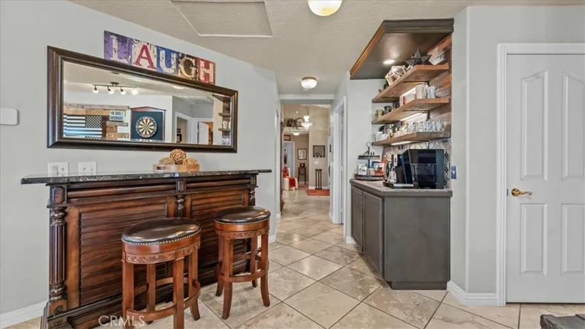 Dedicated bar and serving area with open shelving and custom cabinetry