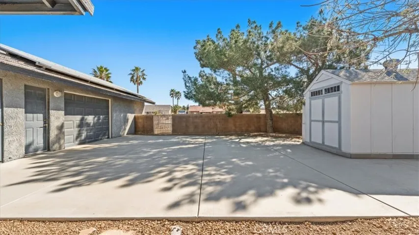 Drive-through garage access to side yard with concrete pad and storage shed—ideal for additional parking or utility use