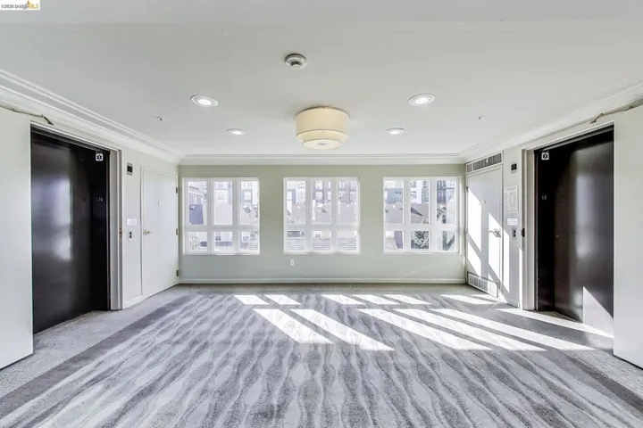 Unfurnished bedroom featuring ornamental molding, elevator, light carpet, and recessed lighting