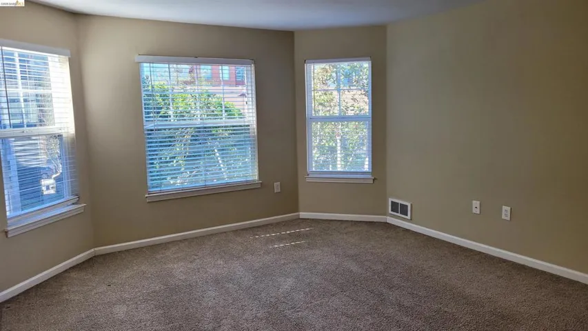 Unfurnished room with baseboards and dark carpet