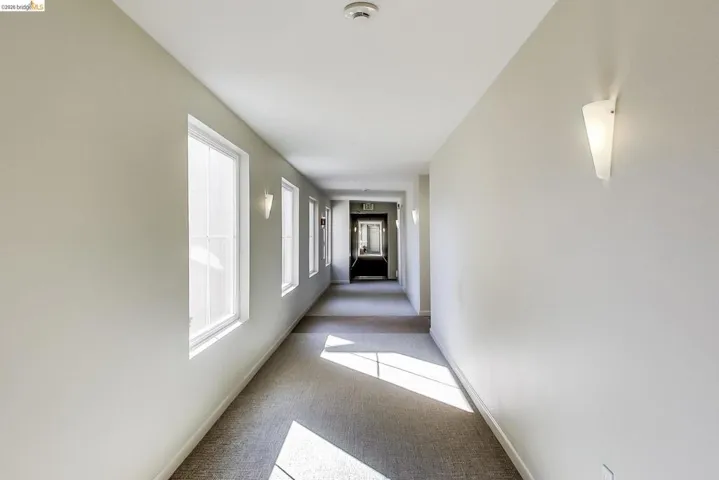 Hallway with light carpet and baseboards