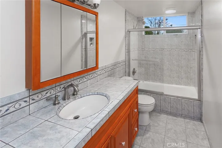 A full bathroom with a step-in glass-enclosed shower and built-in linen storage, along with a hallway linen closet, adds both function and convenience.