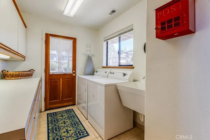 The large laundry room has a plethora of cabinetry, sink, and a door to the exterior yard space.