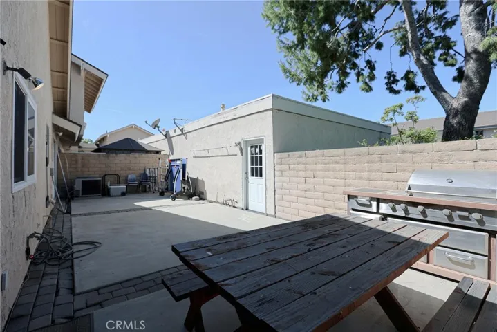Oversized backyard/courtyard with BBQ grill and picnic table.