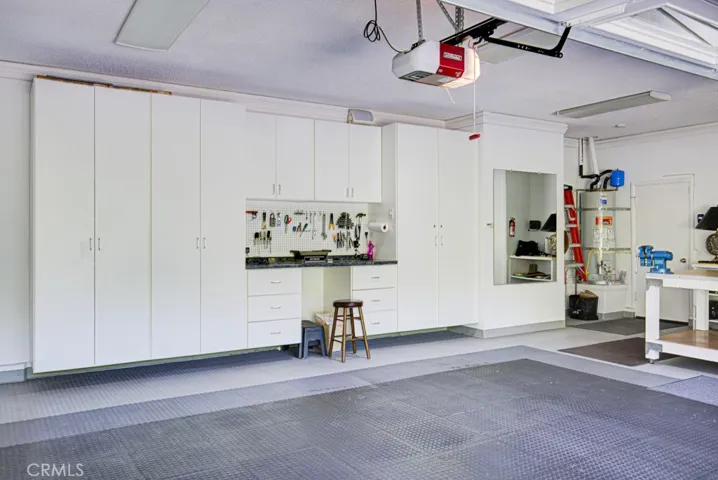Enormous garage easily accommodates two vehicles plus golf cart. Note the many storage cabinets.