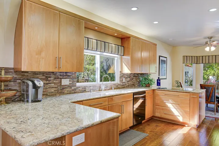 Kitchen features granite countertops, gorgeous wood cabinetry with soft-close drawers, attractive tile backsplash, pots and pans drawers, spice drawer, multiple lazy susans, built-in trash/recycling drawer and breakfast bar that seats two (partially seen at far left).