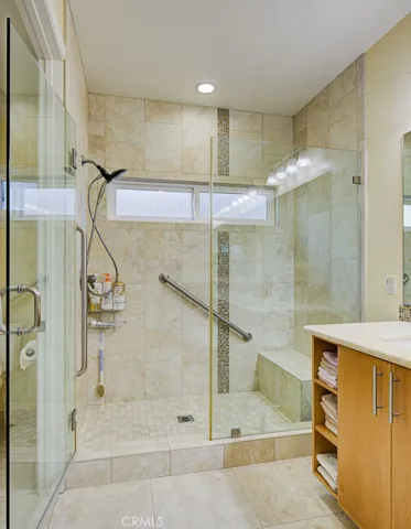 Primary bathroom shower has a convenient seat and grab bars.