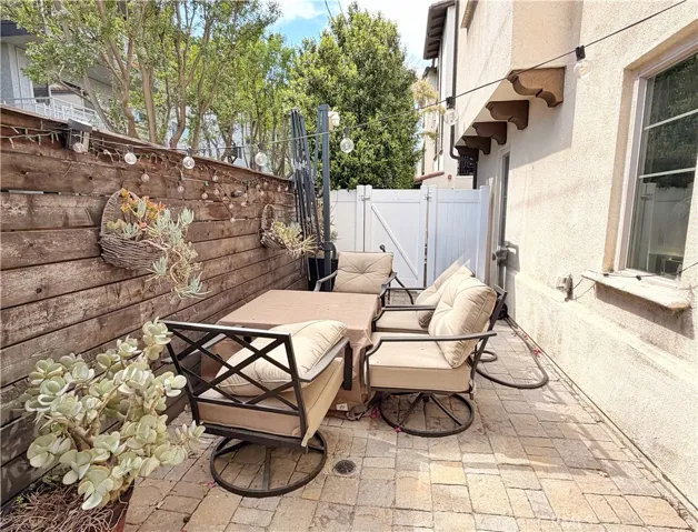 Private backyard patio with pavers and horizontal wood panel feature wall, one of only six in community
