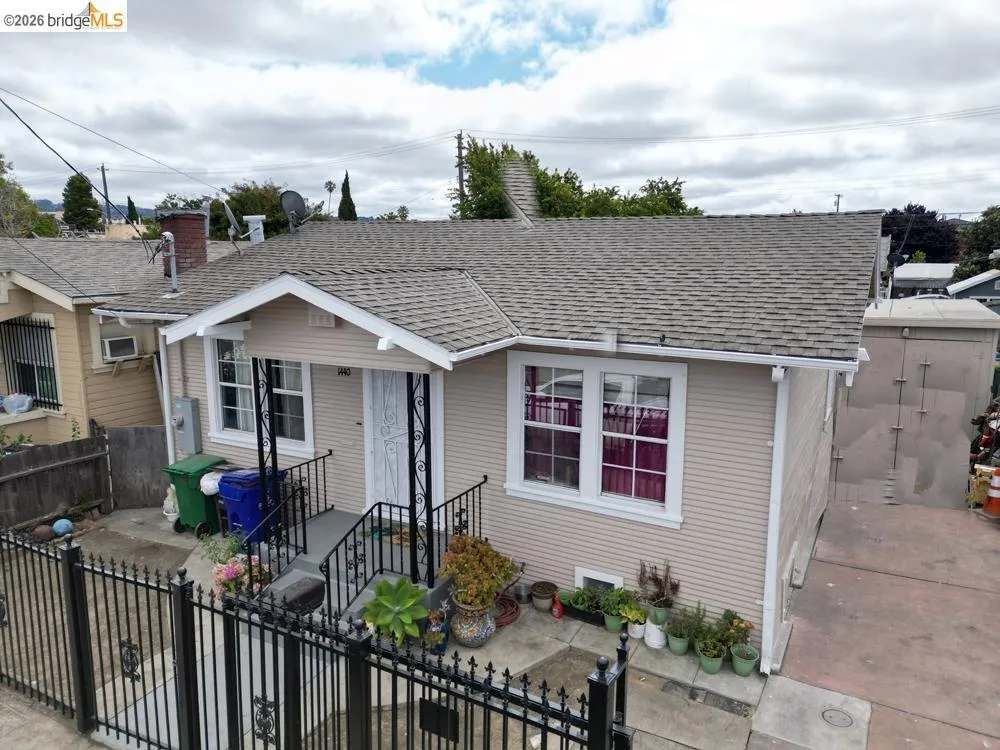 Bungalow-style home featuring a fenced front yard, a shingled roof, and a gate