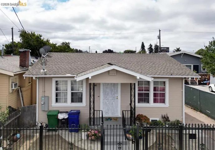 Bungalow-style house featuring a fenced front yard, roof with shingles, and a gate