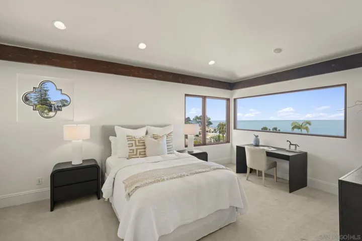 Guest bedroom with a window that frames the ocean, offering a peaceful retreat where soft light and coastal views greet each morning.