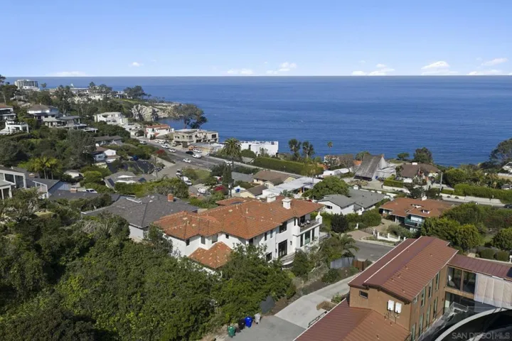 Sweeping aerial perspective capturing the coastline, where endless blue ocean meets the charm of La Jolla’s hillside neighborhoods, offering a setting defined by oceanfront beauty and everyday coastal living.
