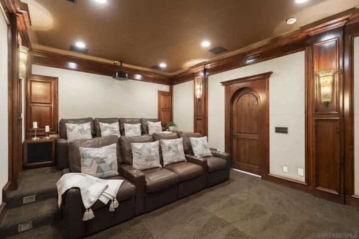 High-tech home theater with tiered leather seating and rich wood paneling, designed for an immersive cinematic experience in a private, refined setting.